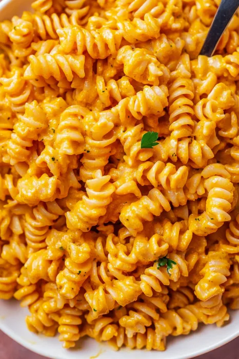A bowl of pasta with a green herb on top.