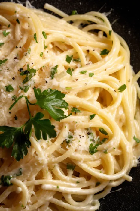 A serving bowl of spaghetti topped with herbs.