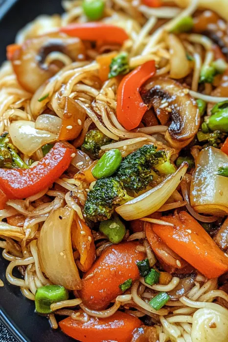 A plate of food with noodles, broccoli, carrots, and peppers.