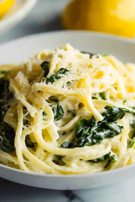 A bowl of pasta with spinach and cheese.