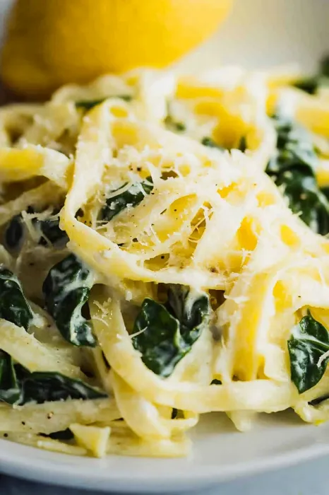 A close up of a plate of pasta with spinach.