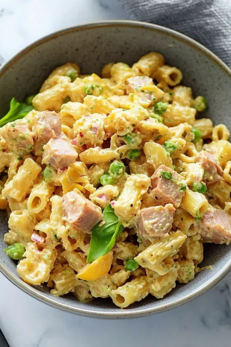 A bowl of pasta with meat and peas.