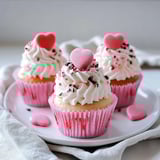 Three cupcakes with hearts on them.