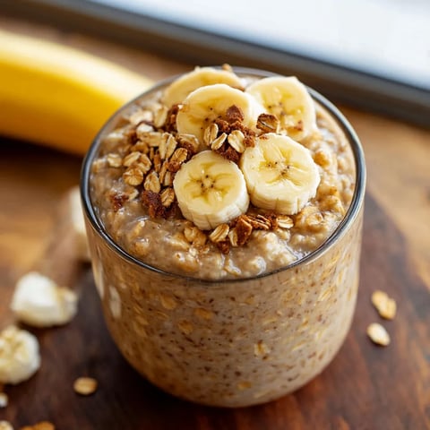 Oats in a glass cup topped with banana slices.